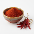 Chilli powder in a ceramic bowl with dried red chillies on white background