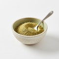 Ground cardamom powder in a ceramic bowl on white background