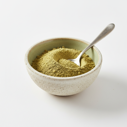 Ground cardamom powder in a ceramic bowl on white background