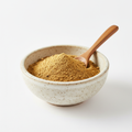 Ground coriander powder in a ceramic bowl on white background
