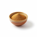 Ground nutmeg powder in a ceramic bowl on white background