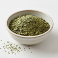 Dried basil leaves in a ceramic bowl on white background