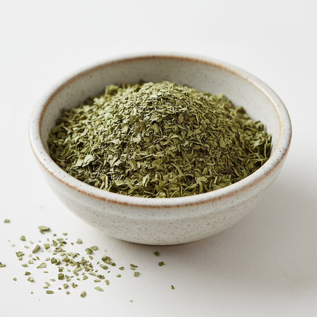 Dried basil leaves in a ceramic bowl on white background