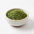 Dried parsley flakes in a ceramic bowl on white background